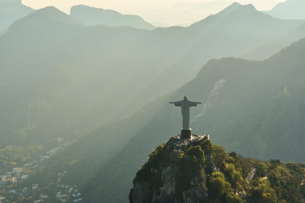 Imagem aérea do Cristo Redentor, vê-se de longe parte da cidade e a região serrana.