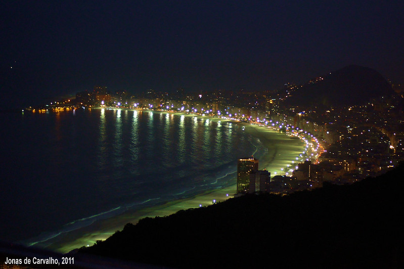 Foto noturna da praia de Copacabana. Areia da praia iluminada.