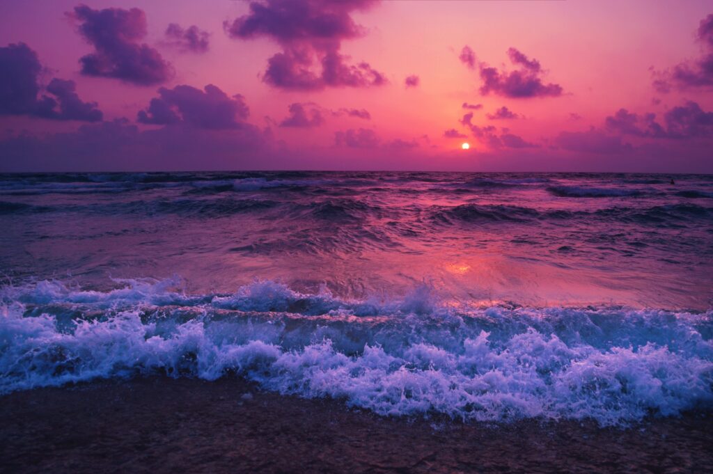 Inesquecível por do sol a beira da praia. Ondas quebrando contrastando o branco com as cores avermelhadas do por do sol.