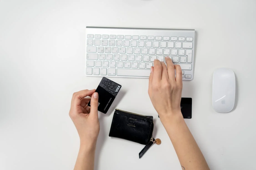 Pessoa comprando online, teclado e cartão de crédito.