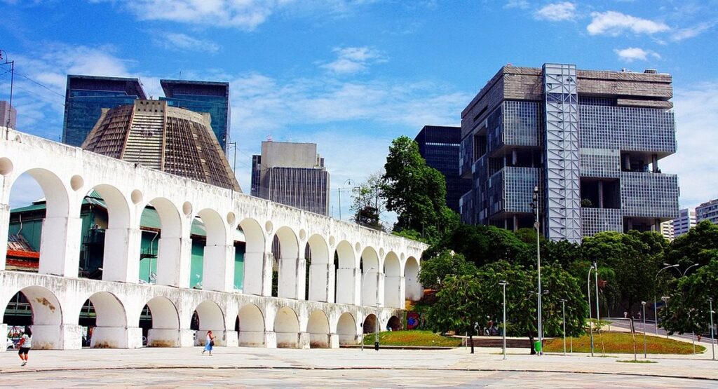 Foto dos Arcos da Lapa, pessoas passando por baixo. Dia de Sol.