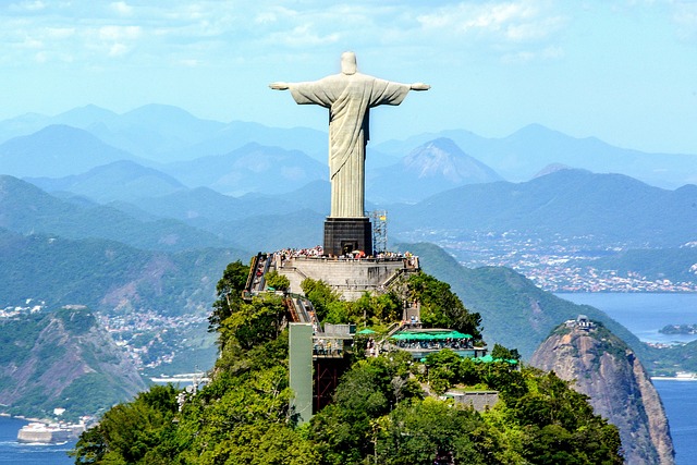 Imagem do Cristo, pessoas visitando, Rio de Janeiro ao fundo. Dia de Sol.