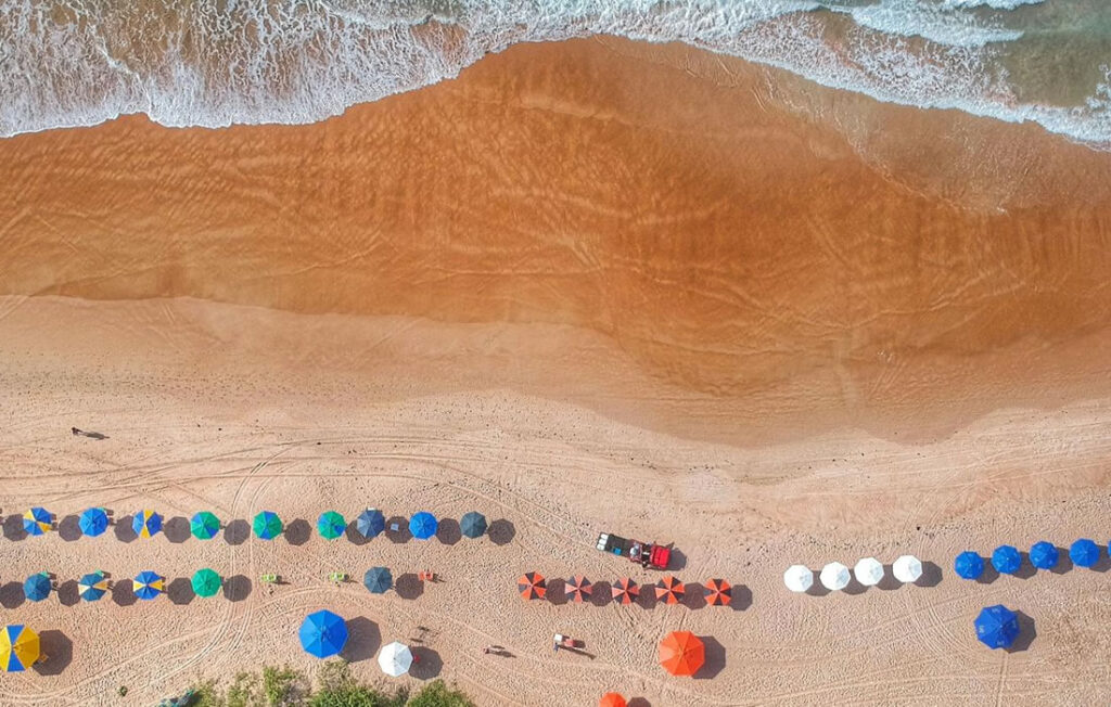 Foto tirada por drone da praia de Geribá em Búzios, guarda-sois na areia da praia.