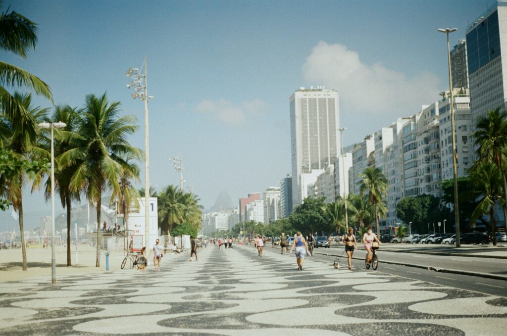 Pessoas andando no calçadão da praia de Copacabana.