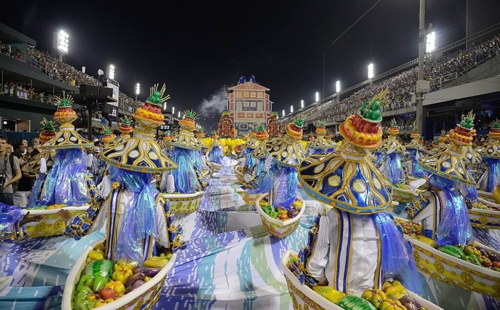 Desfile no sambódromo, pessoas fantasiadas na avenida do samba.