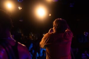 Cantor no palco com plateia iluminada em show de música ao vivo, como os shows de Roberto Carlos no Qualistage