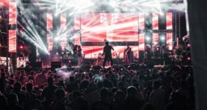 Show de música ao vivo com multidão e luzes coloridas no palco, clima de festival de rock